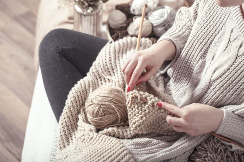 Vintage wooden knitting needles and yarn in woman’s hands