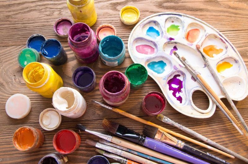 Multicolored plastic cans with paints. Artist workplace background. Old dirty Paints background. Colorful artist palette. Creativity, visual art concept. Art and craft.